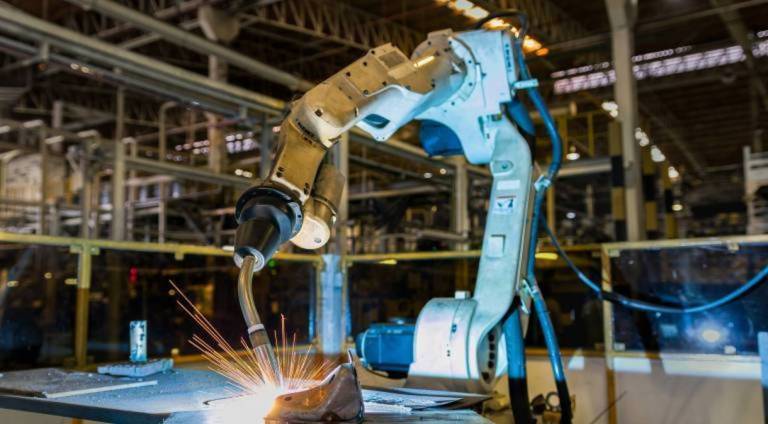 Photo of automated robotic manufacturing equipment welding a product in a factory, a high resolution image representing a best practice in industrial website design and manufacturer marketing