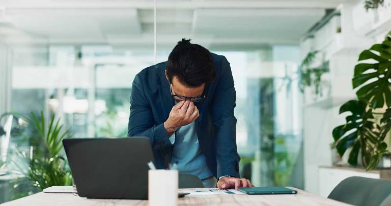 stressed businessman leaning over a desk in an office, representing the hidden business risks of weak digital visibility and lost B2B opportunities