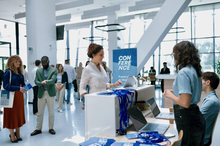 conference attendees checking in and networking at a busy business event, representing the growing importance of digital presence before major B2B trade shows and conferences