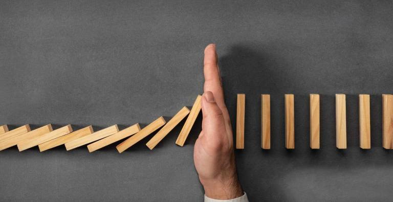 hand stops a row of falling dominoes, representing the removal of friction in SaaS onboarding and trials to prevent drop-off and keep users moving toward activation and conversion