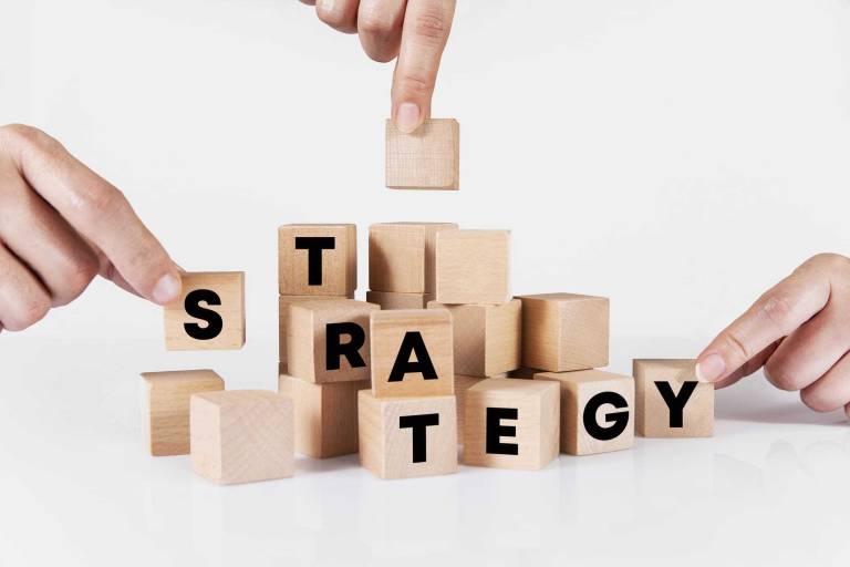 hands arranging wooden blocks that spell strategy, symbolizing the shift from feature-focused messaging to structured, value-led storytelling that highlights outcomes and business impact for SaaS buyer
