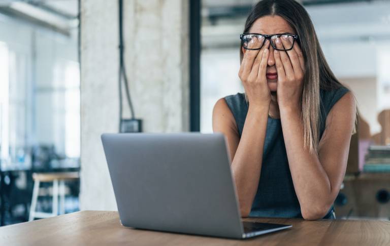 Tired exhausted employee at computer rubbing eyes