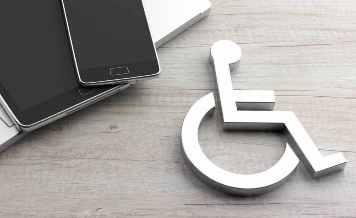 Laptop and mobile devices with wheelchair icon on wooded surface