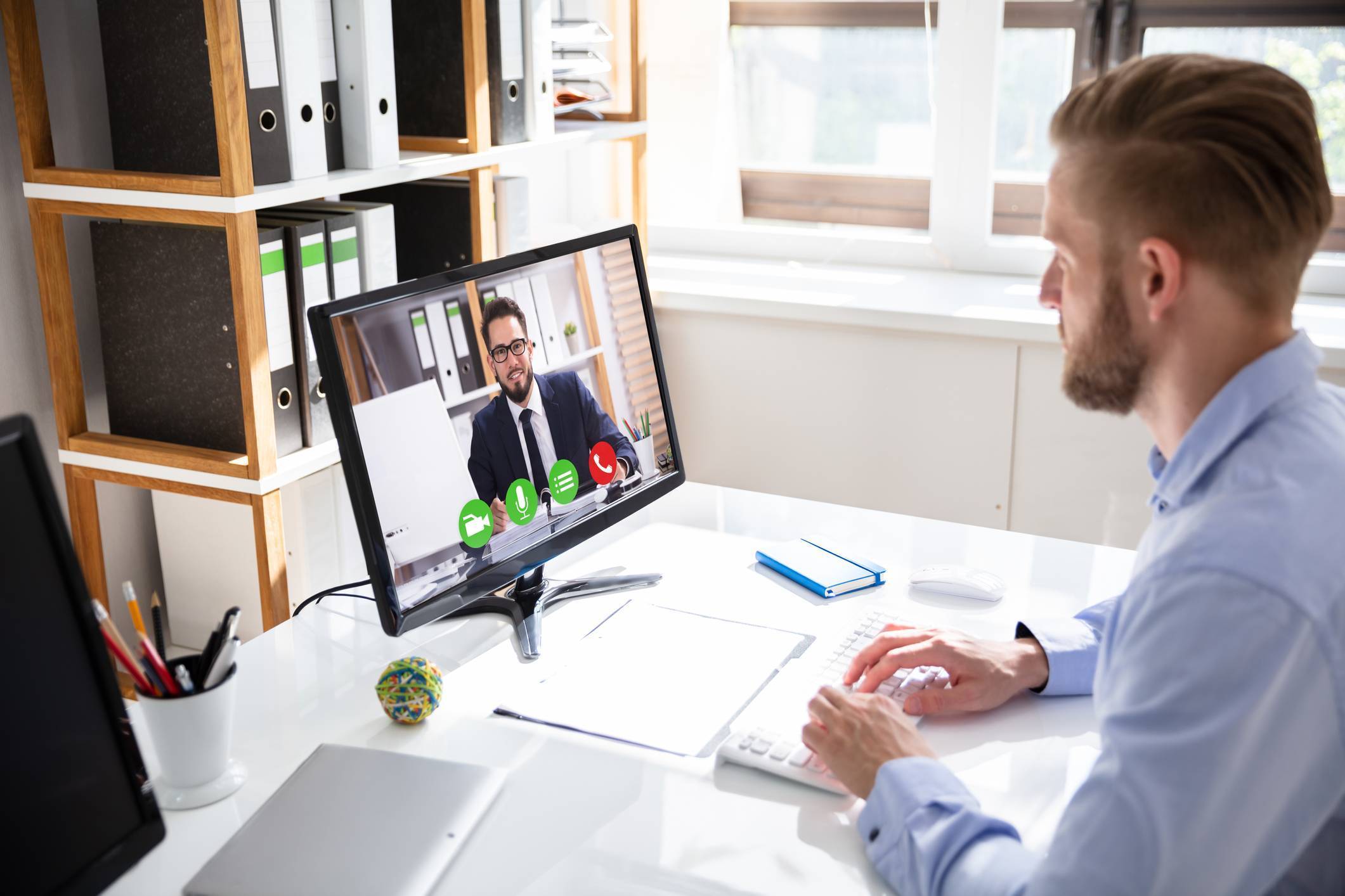 business man video conferencing with sales rep on desktop computer at office desk