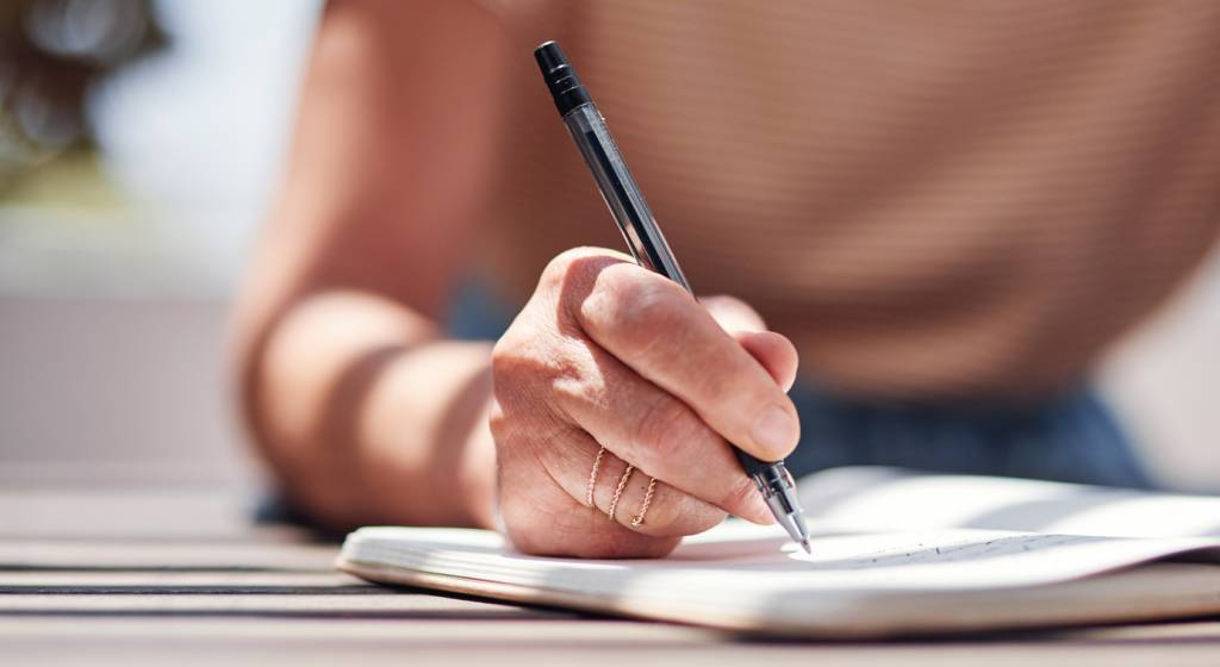 photo of a persons hand writing in a book